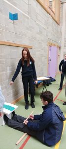 Students working together in a gym, measuring length. 