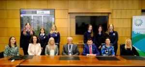 Group of people sitting behind a desk.