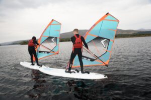Two people windsurfing on a lake 