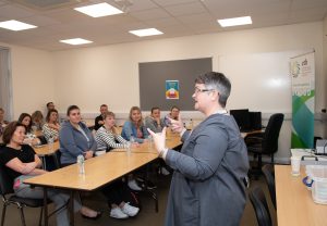 Person talking to a group of people in a classroom. 