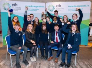 Group of students and staff sitting and standing, with hands waving. 