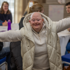 Person smiling at the camera with arms outstretched.
